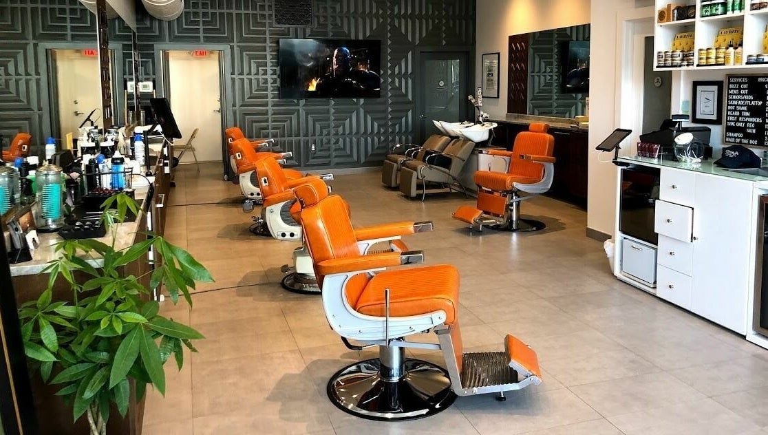 Orange barber chairs lined up at Dennis J's Barbershop in Fort Lauderdale, Florida, US, showcasing modern design.