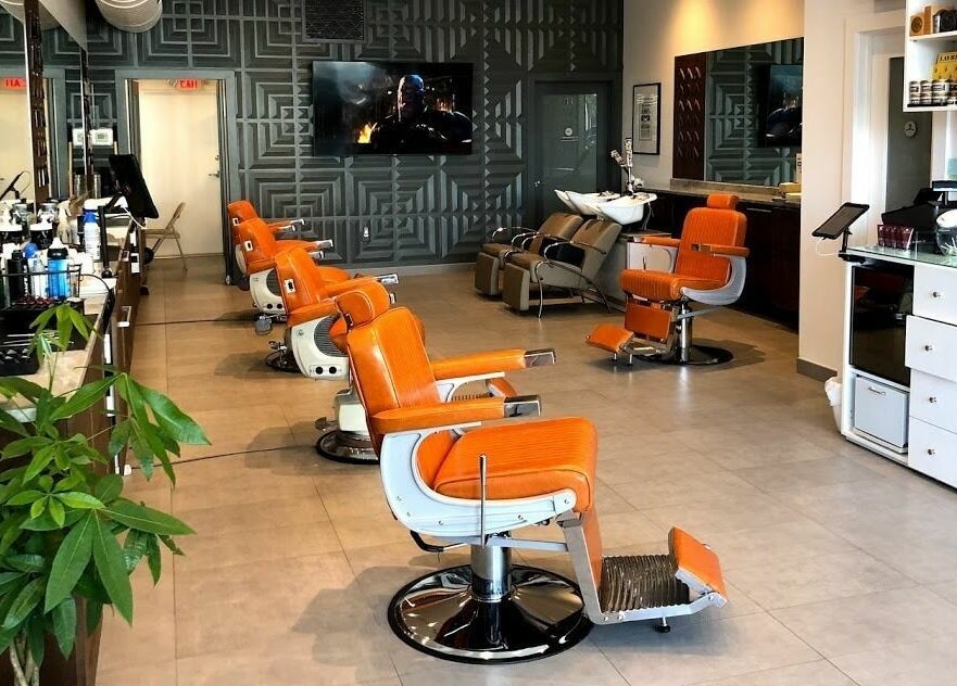 Orange barber chairs lined up at Dennis J's Barbershop in Fort Lauderdale, Florida, US, showcasing modern design.