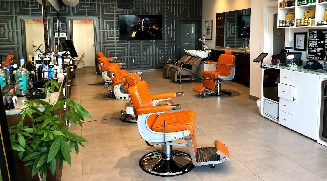 Orange barber chairs lined up at Dennis J's Barbershop in Fort Lauderdale, Florida, US, showcasing modern design.
