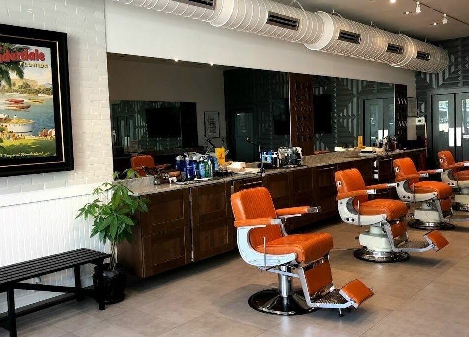 Inside Dennis J's Barbershop in Fort Lauderdale, Florida, retro orange chairs line up against mirrored walls.