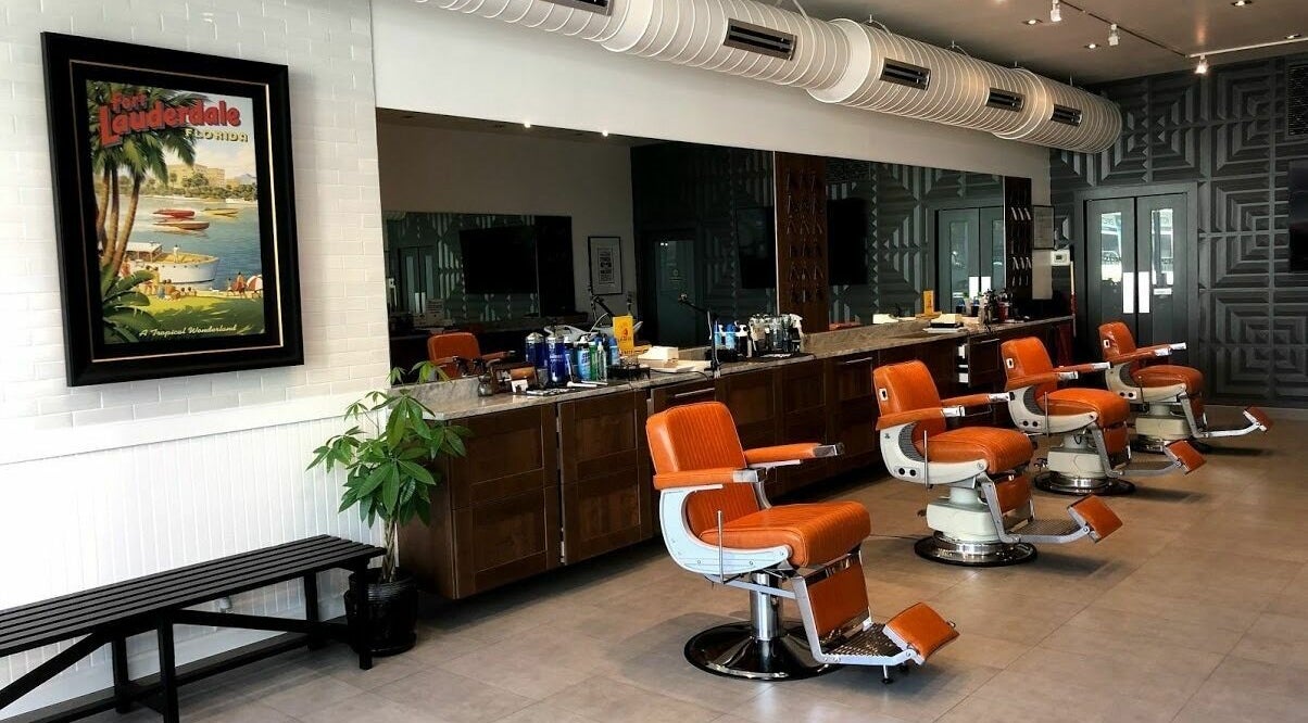Inside Dennis J's Barbershop in Fort Lauderdale, Florida, retro orange chairs line up against mirrored walls.