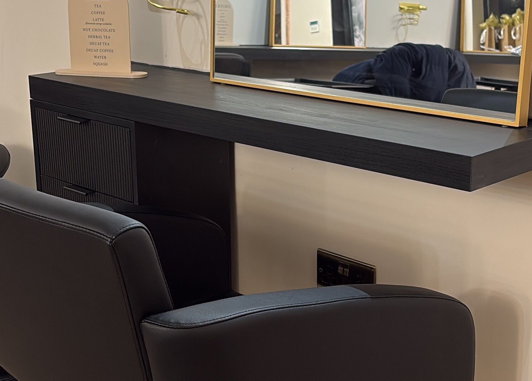 Modern styling station at THE Hairdressers in Lowestoft, England, GB featuring elegant black furnishings.