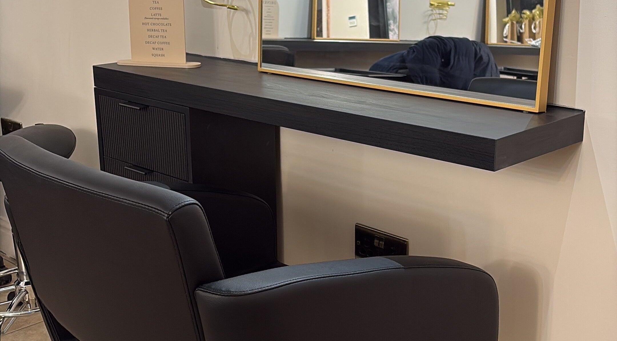 Modern styling station at THE Hairdressers in Lowestoft, England, GB featuring elegant black furnishings.