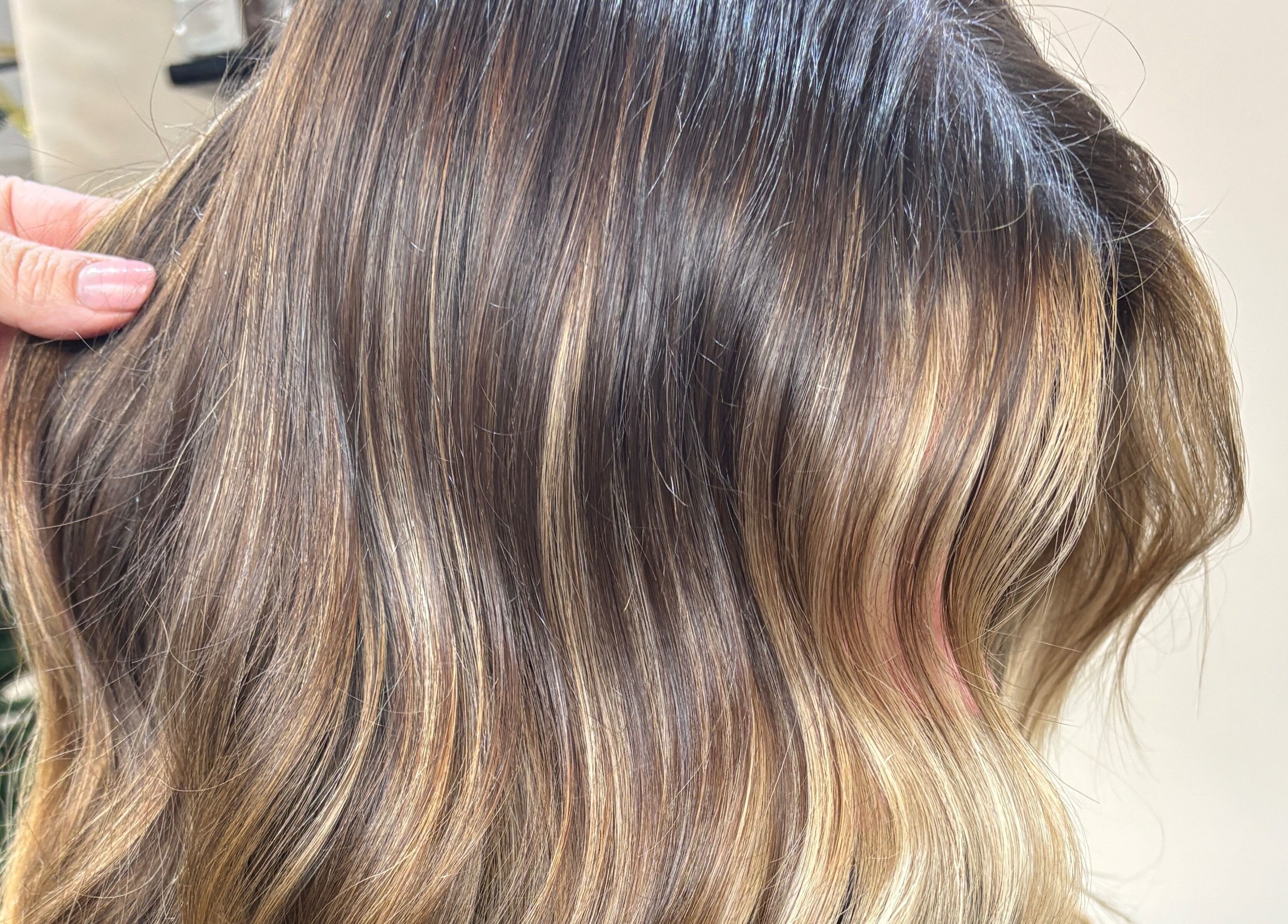 Silky blonde wavy hair styled at THE Hairdressers in Lowestoft, England, GB against a cozy background.