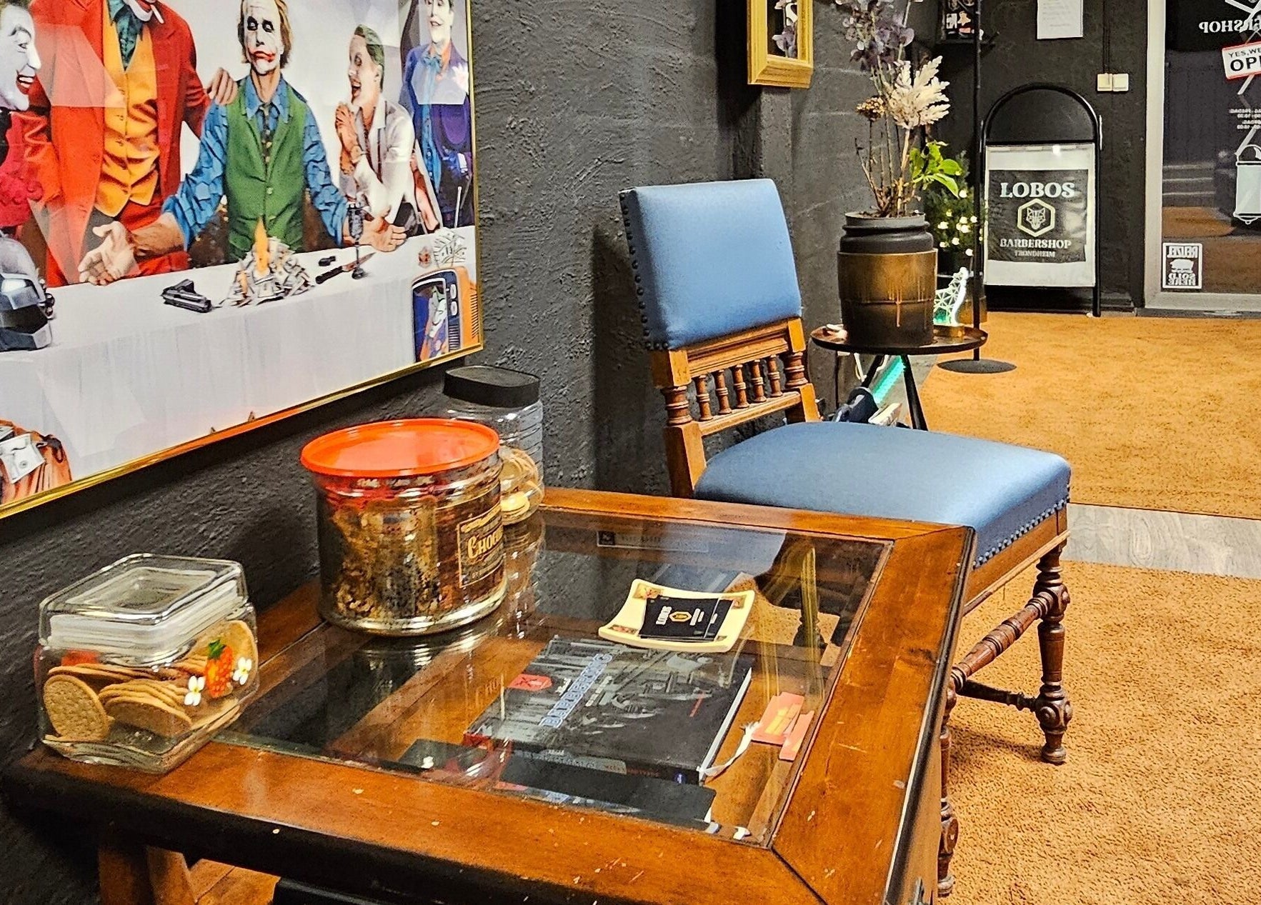 Koselig loungeområde i Lobos Barbershop Trondheim, Trøndelag, NO med kunstverk og innbydende møbler.