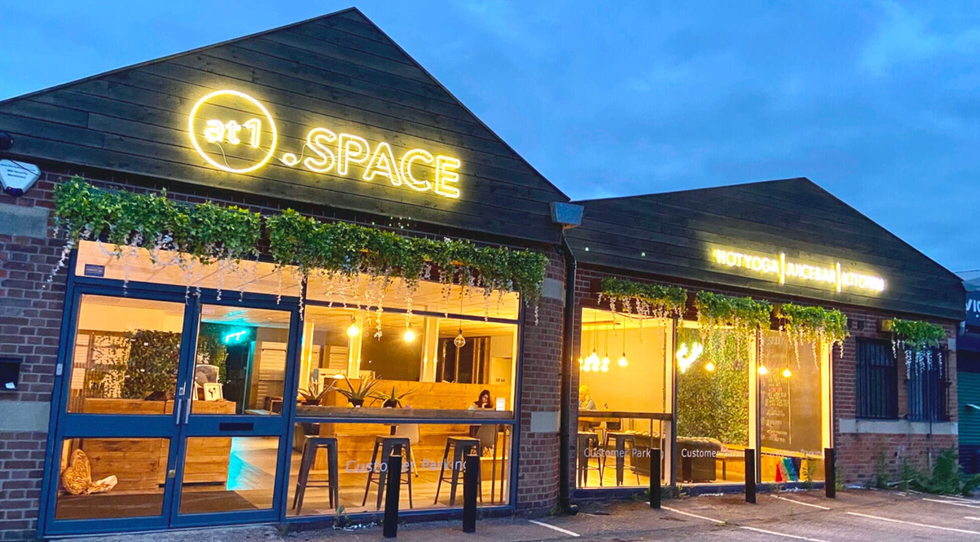 At1.Aesthetics venue in Nottingham, England, GB, with lit signs and greenery exterior.