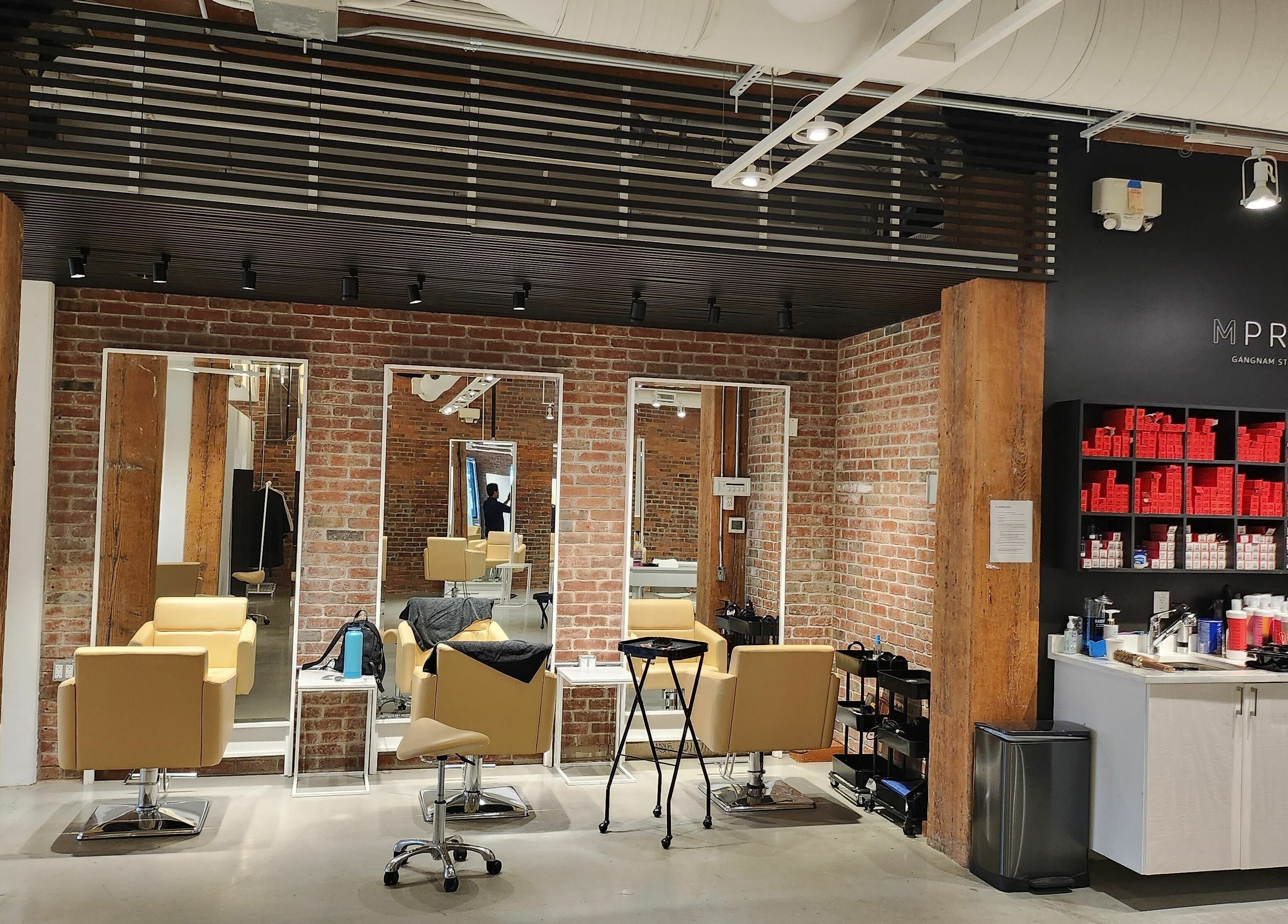 Modern salon interior at M Prive Salon in Vancouver, BC, CA with stylish chairs and exposed brick walls.