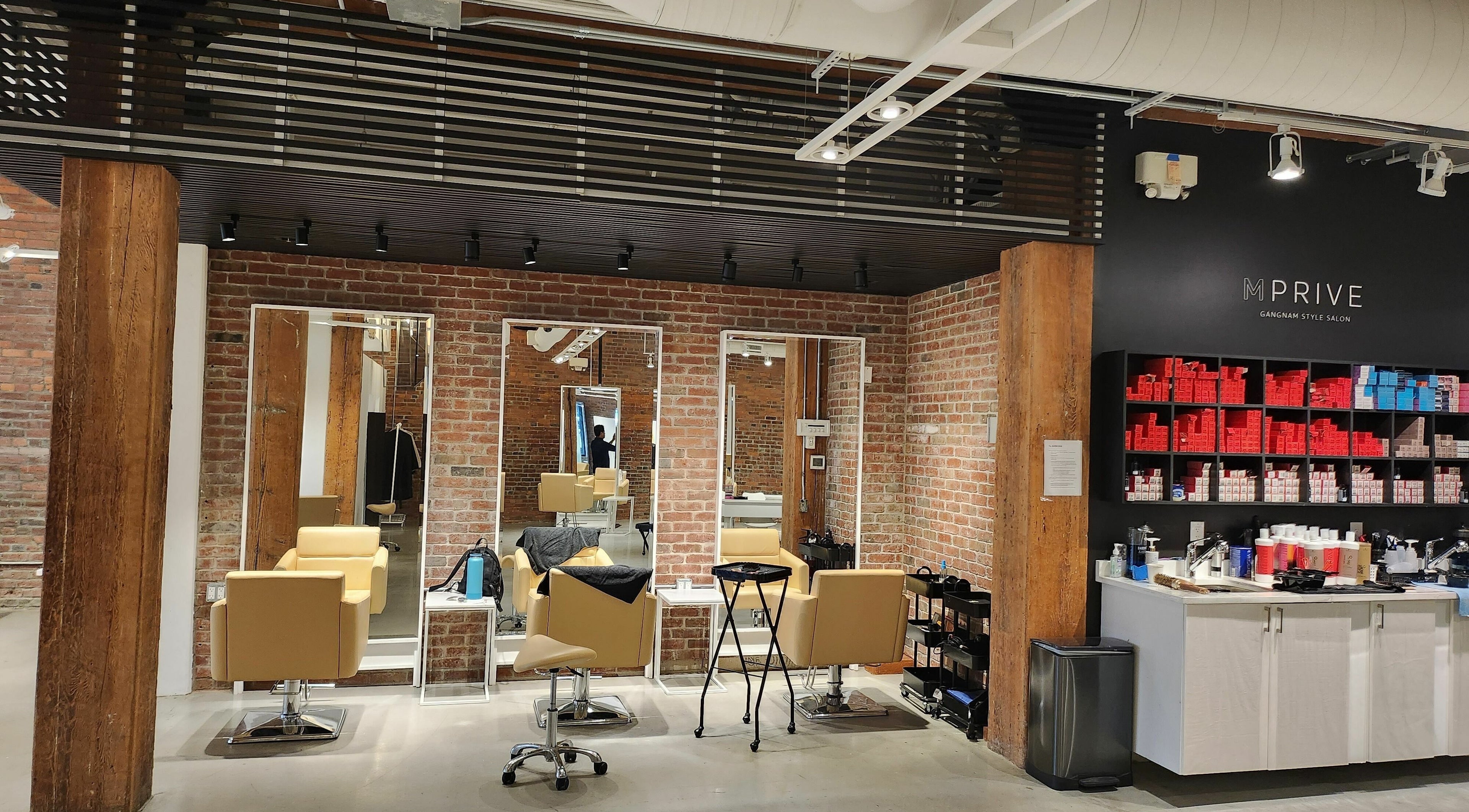 Modern salon interior at M Prive Salon in Vancouver, BC, CA with stylish chairs and exposed brick walls.