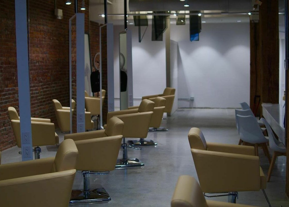 Stylish interior of M Prive Salon in Vancouver, British Columbia, CA with modern seating and exposed brick wall.