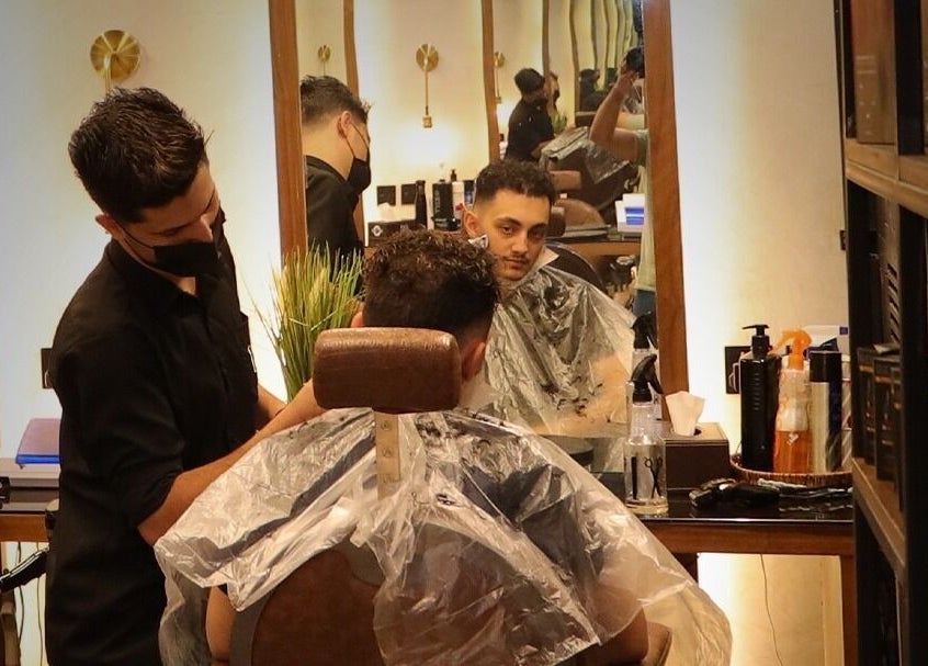Customer enjoying a haircut at Dar Dujour Men in الرياض, منطقة الرياض, SA. Stylish salon interior visible in mirror.