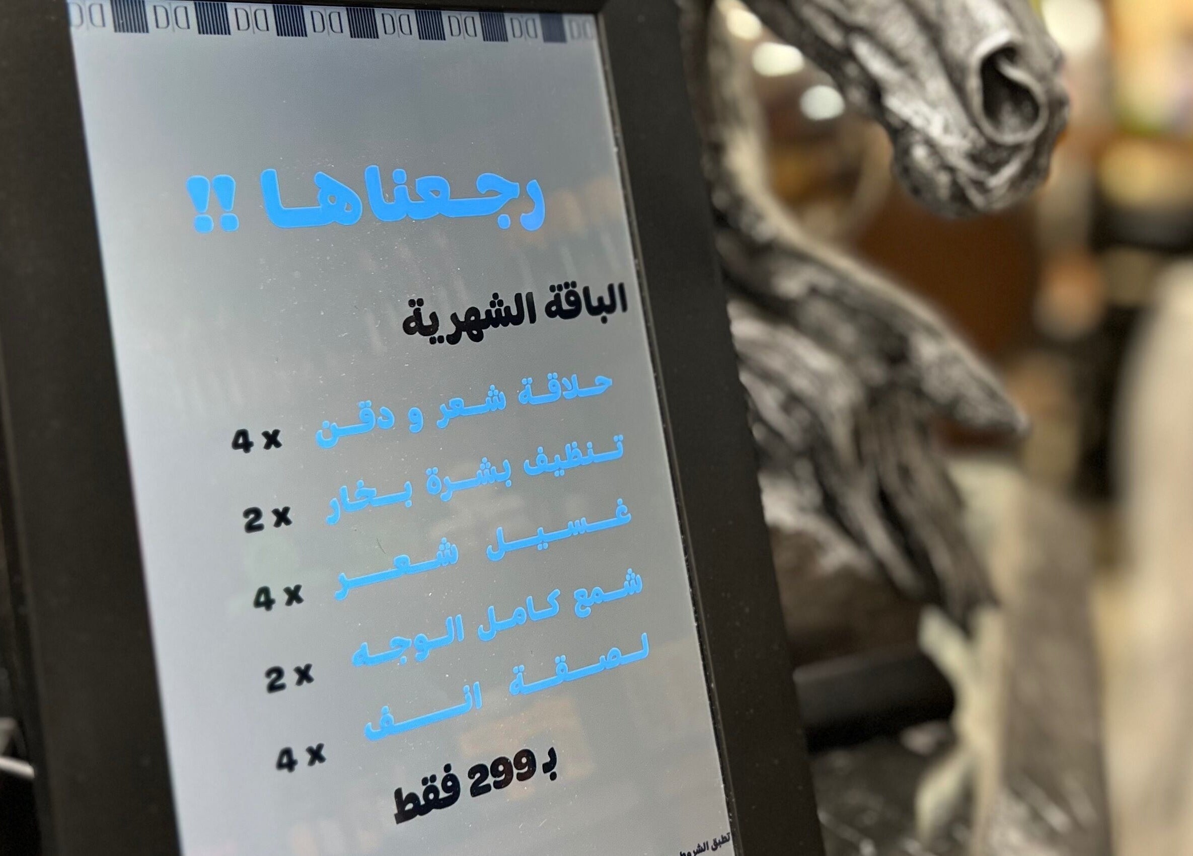 Tablet displays monthly offers at Dar Dujour Men, الرياض, منطقة الرياض, SA, showcasing hair and skincare services.