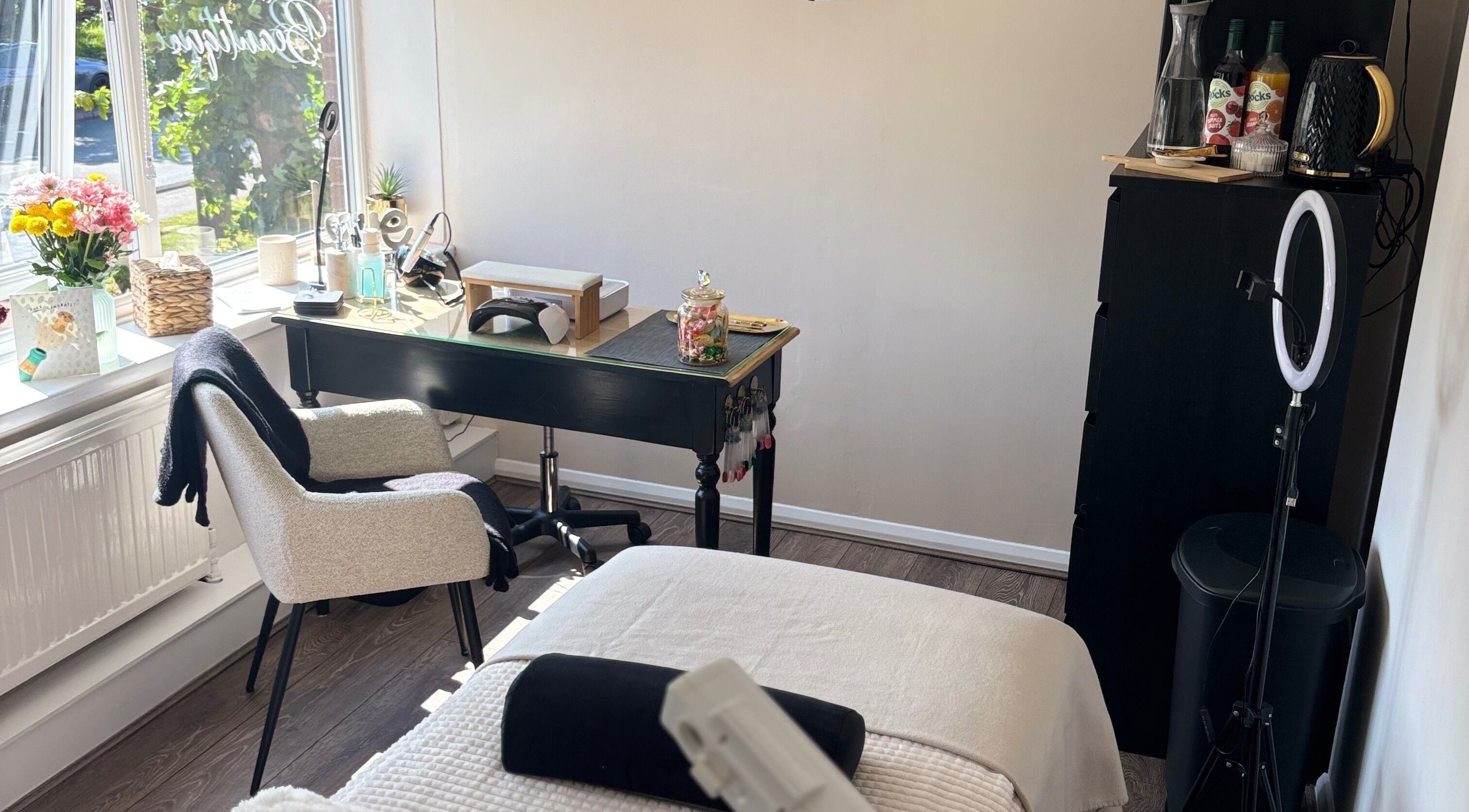 Calm beauty treatment room at The Beautique, Atherstone, England, GB with chair, flowers, and natural light.