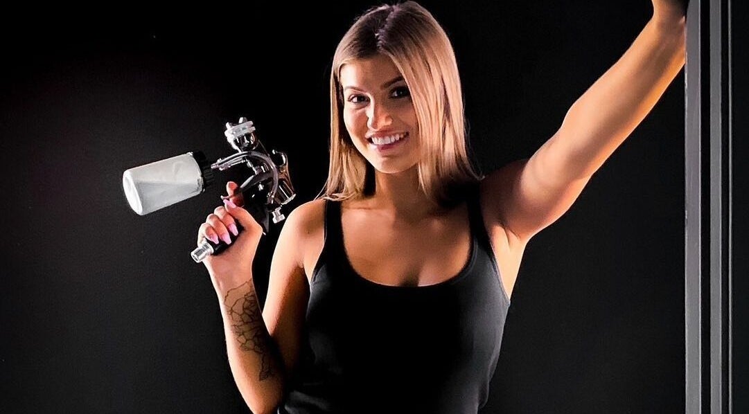 Spray artist smiling at Sol Sunless Tanning - Dallas Mockingbird, Dallas, Texas, US with tanning equipment.