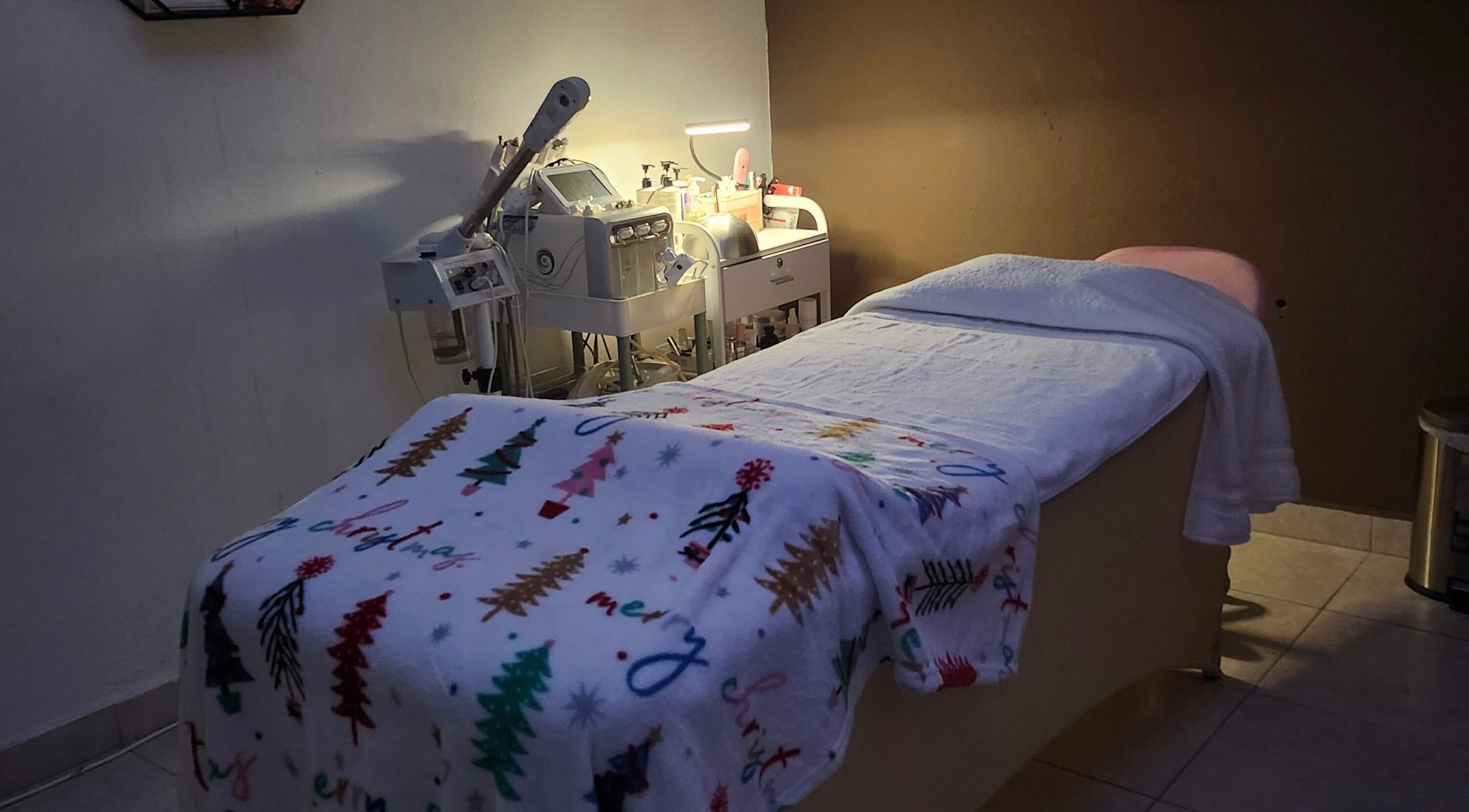 Cama de tratamiento en Skincare by AB, San Juan, San Juan, PR, con equipo de belleza y manta festiva.