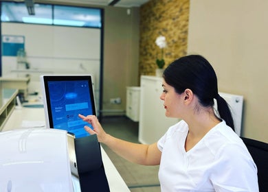 Staff member at Boni Beauty Clinic in Luxembourg using a touchscreen at the reception area.