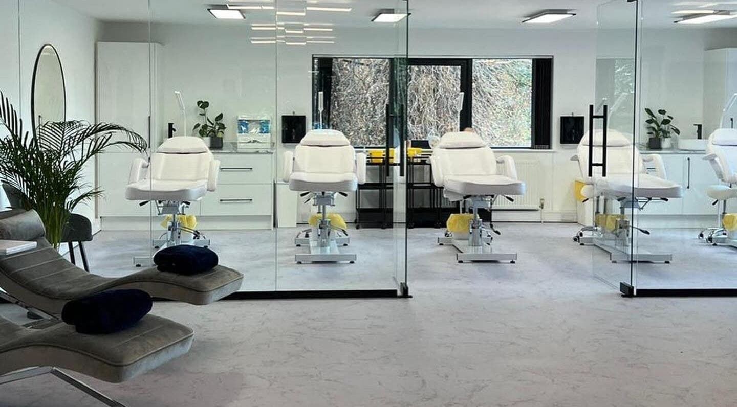 Modern treatment room at Belle Femme Aesthetics & Training Academy, Shirley, England, GB with white chairs and glass walls.