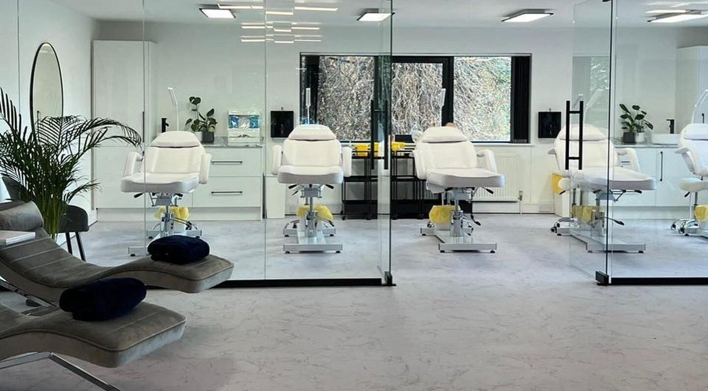 Modern treatment room at Belle Femme Aesthetics & Training Academy, Shirley, England, GB with white chairs and glass walls.
