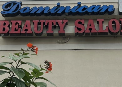 Signage of Dominican Salon - West Kendall with vibrant flowers in Miami, Florida, US.