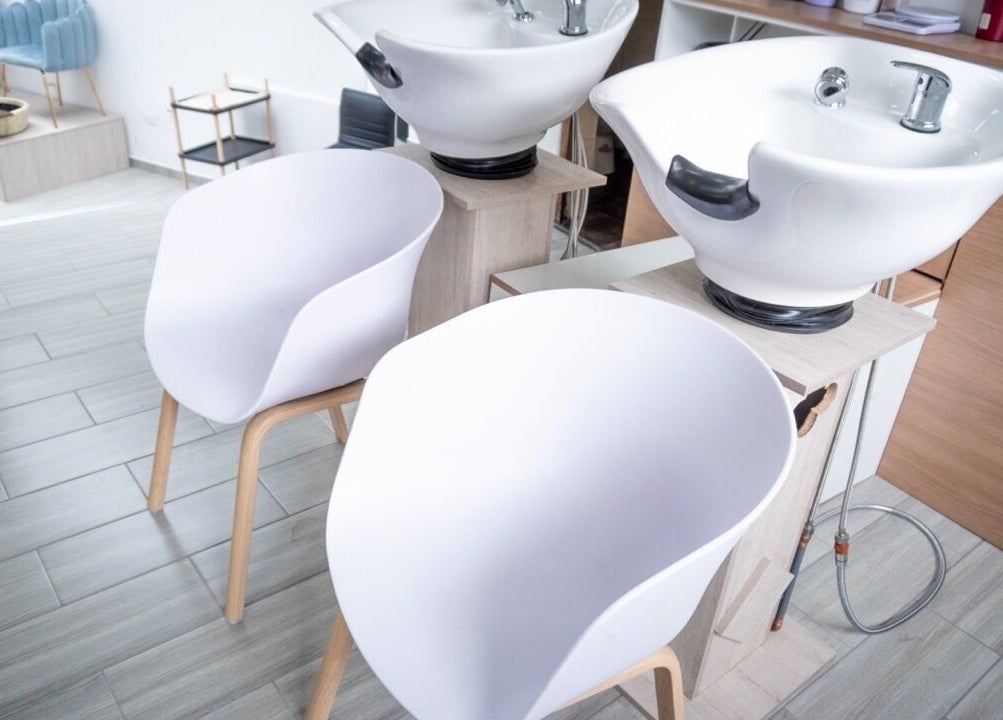 Estación de lavado moderna en Uio Color Peluqueria, Sheridan, Wyoming, US, con sillas y lavabos blancos.