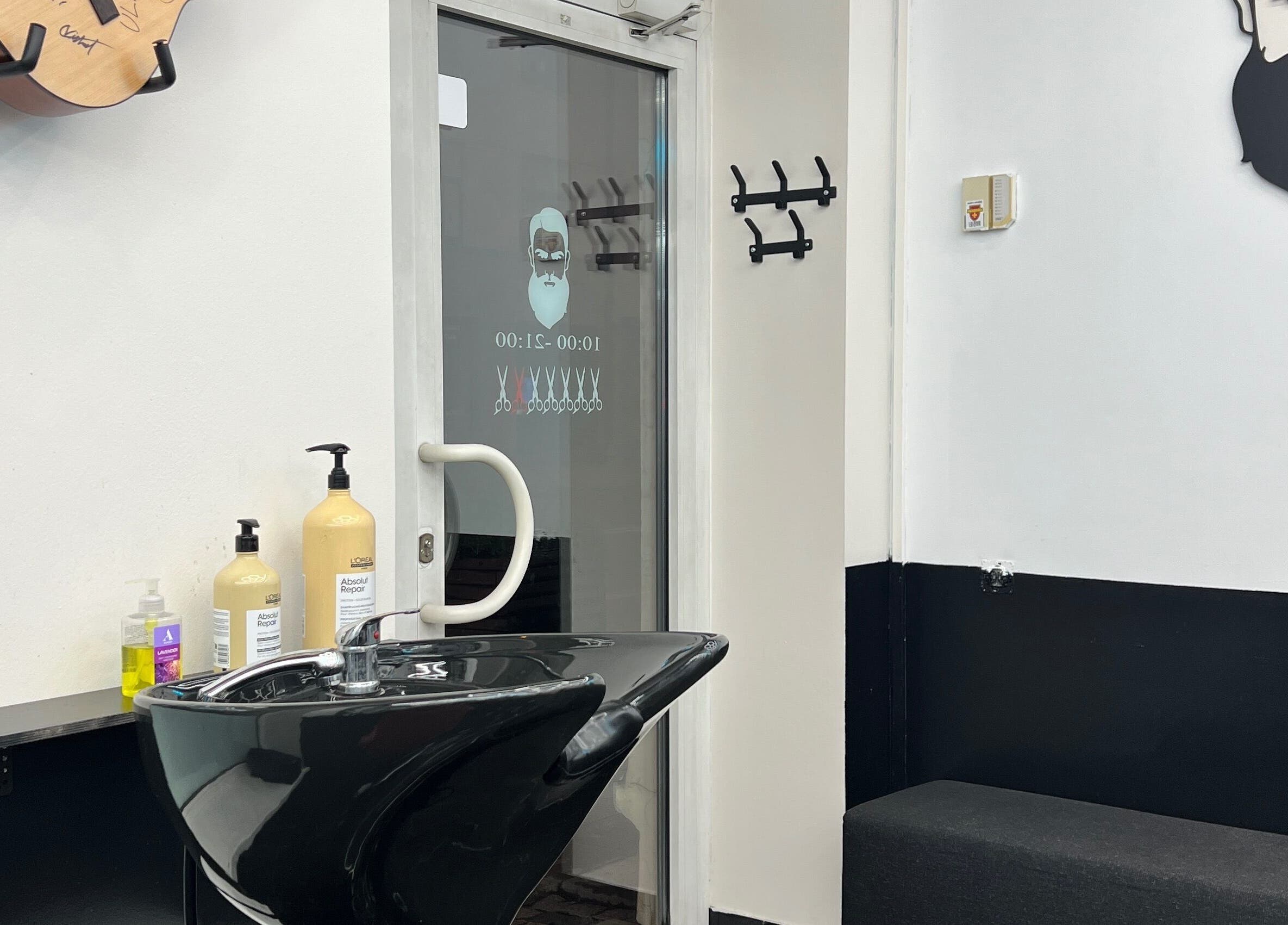 Modern barber station at Desi (Aleksandra Caka), Rīga, LV with sleek black sink and hair care products.
