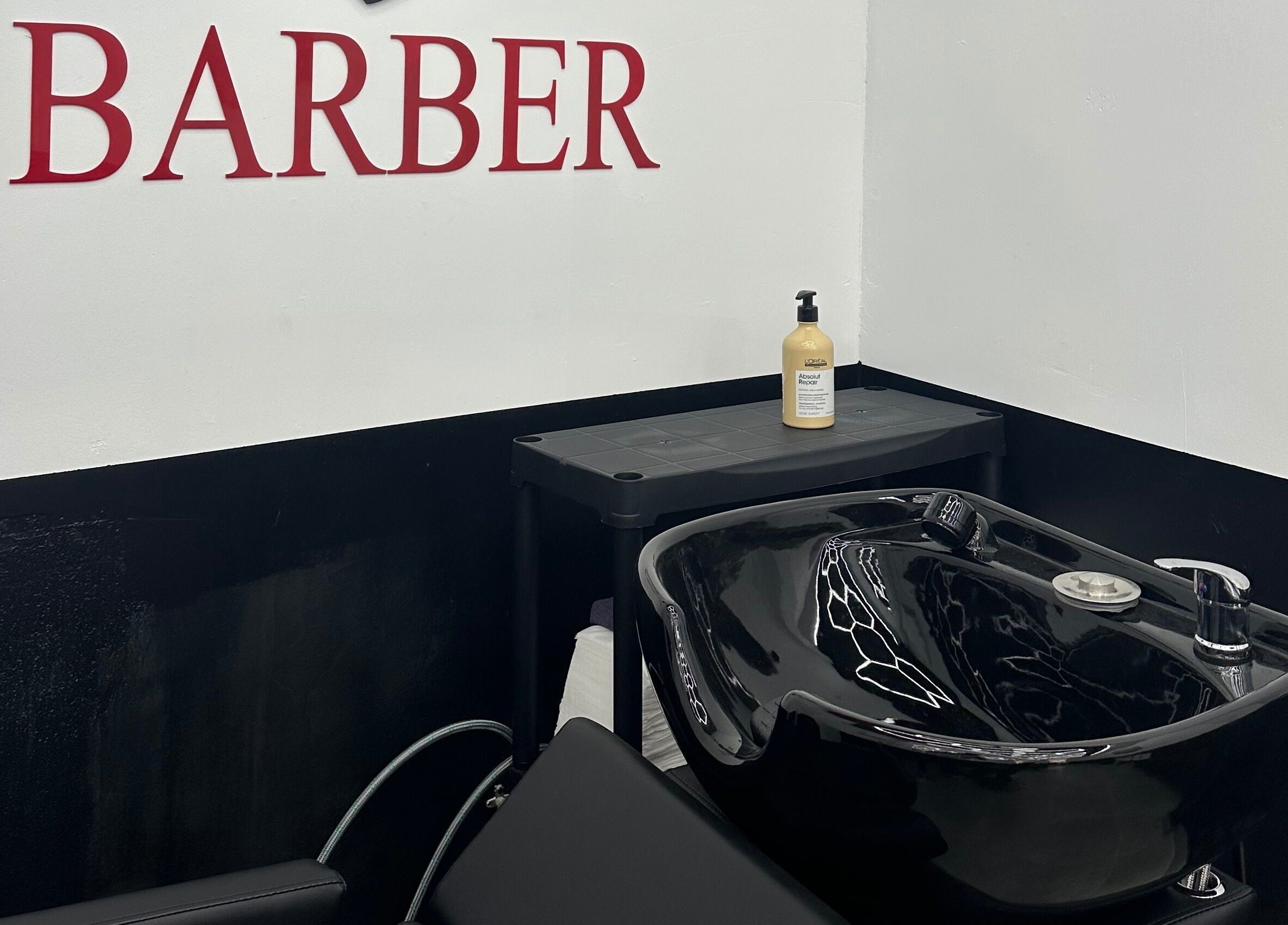 Modern barber station at Desi (Brivibas Iela) in Rīga, LV featuring a black shampoo basin and hair products.