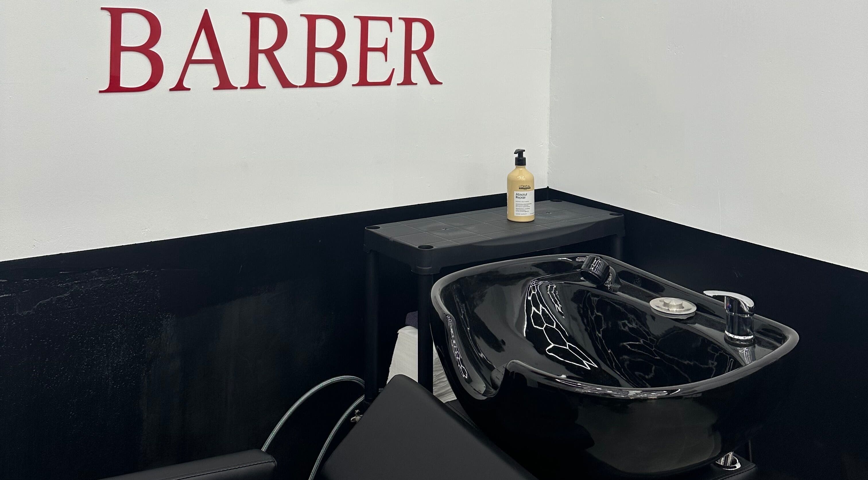 Modern barber station at Desi (Brivibas Iela) in Rīga, LV featuring a black shampoo basin and hair products.