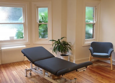 Serene therapy room at Akasha Integrative Health in Manly, New South Wales, AU, featuring a massage table and seating.