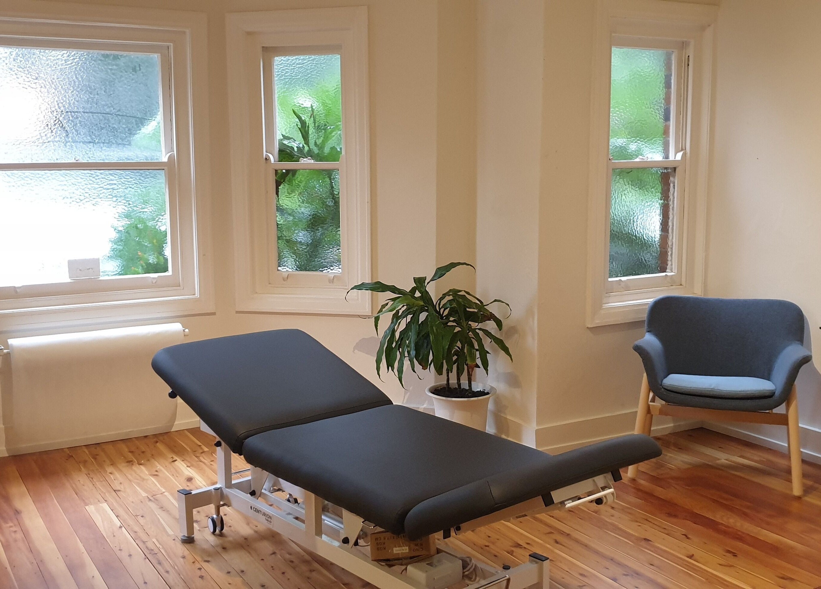 Serene therapy room at Akasha Integrative Health in Manly, New South Wales, AU, featuring a massage table and seating.