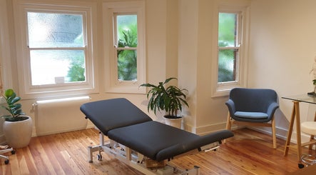 Serene therapy room at Akasha Integrative Health in Manly, New South Wales, AU, featuring a massage table and seating.