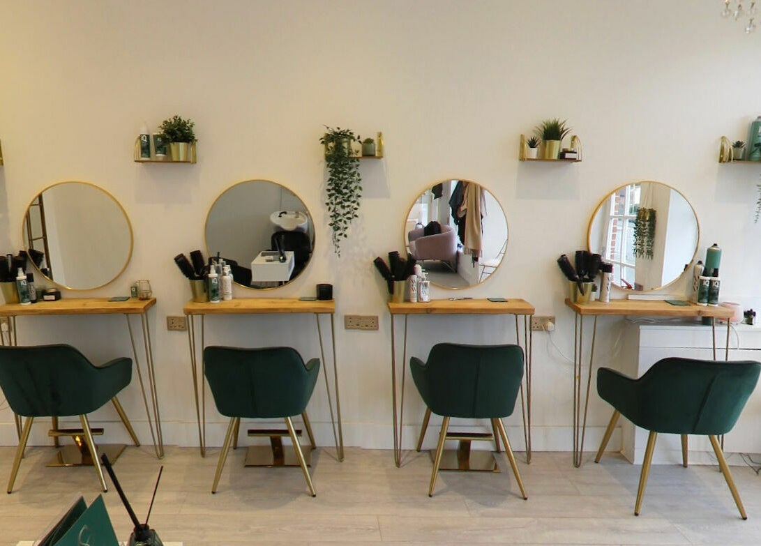 Elegant beauty stations at Studio 66, Broxbourne, England, GB, featuring mirrors and stylish green chairs.