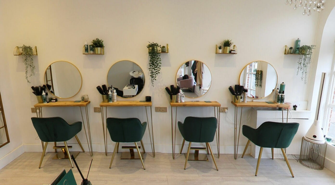 Elegant beauty stations at Studio 66, Broxbourne, England, GB, featuring mirrors and stylish green chairs.
