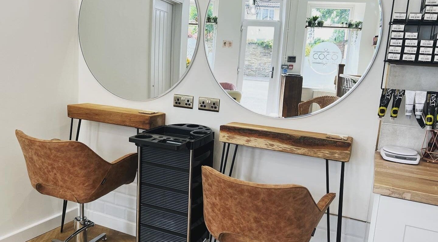 Modern salon setup at Coco Hair and Beauty in Dodworth, England, GB, featuring stylish chairs and round mirrors.