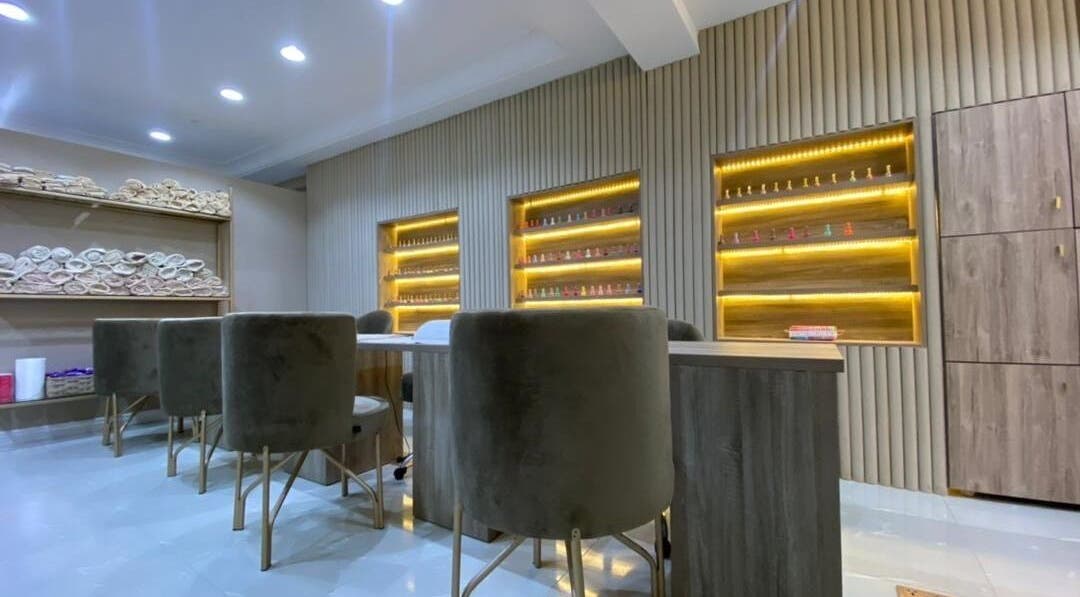 Elegant interior of Sugarcoat Nail Bar, Abuja, featuring plush seating and lit nail polish displays.