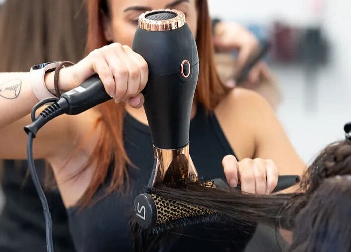 A stylist blow-drying hair at With an Edge Hair, Beauty and Head Spa Ormeau, Ormeau, Queensland, AU.