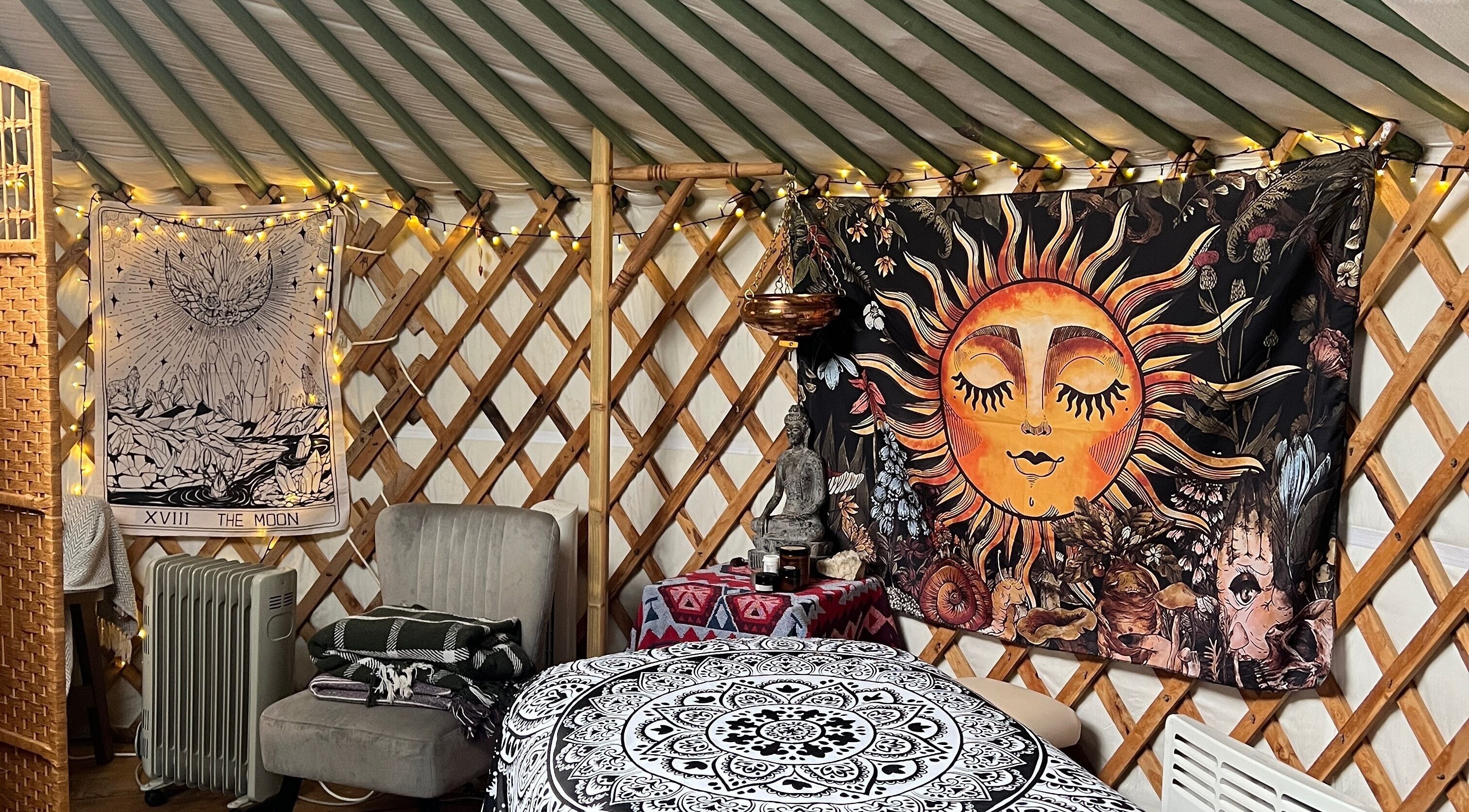 Cozy yurt interior at Wellness in the Wild, Newquay, England, GB with vibrant sun and moon tapestry.
