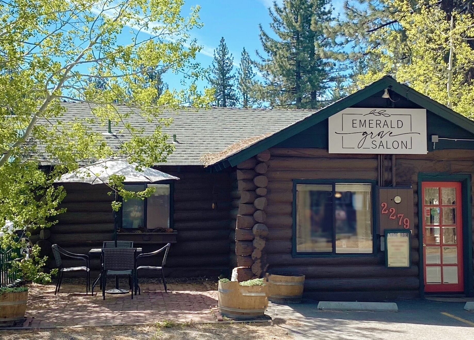 Emerald Grove Salon log cabin exterior in South Lake Tahoe, California, US with vibrant trees and seating area.