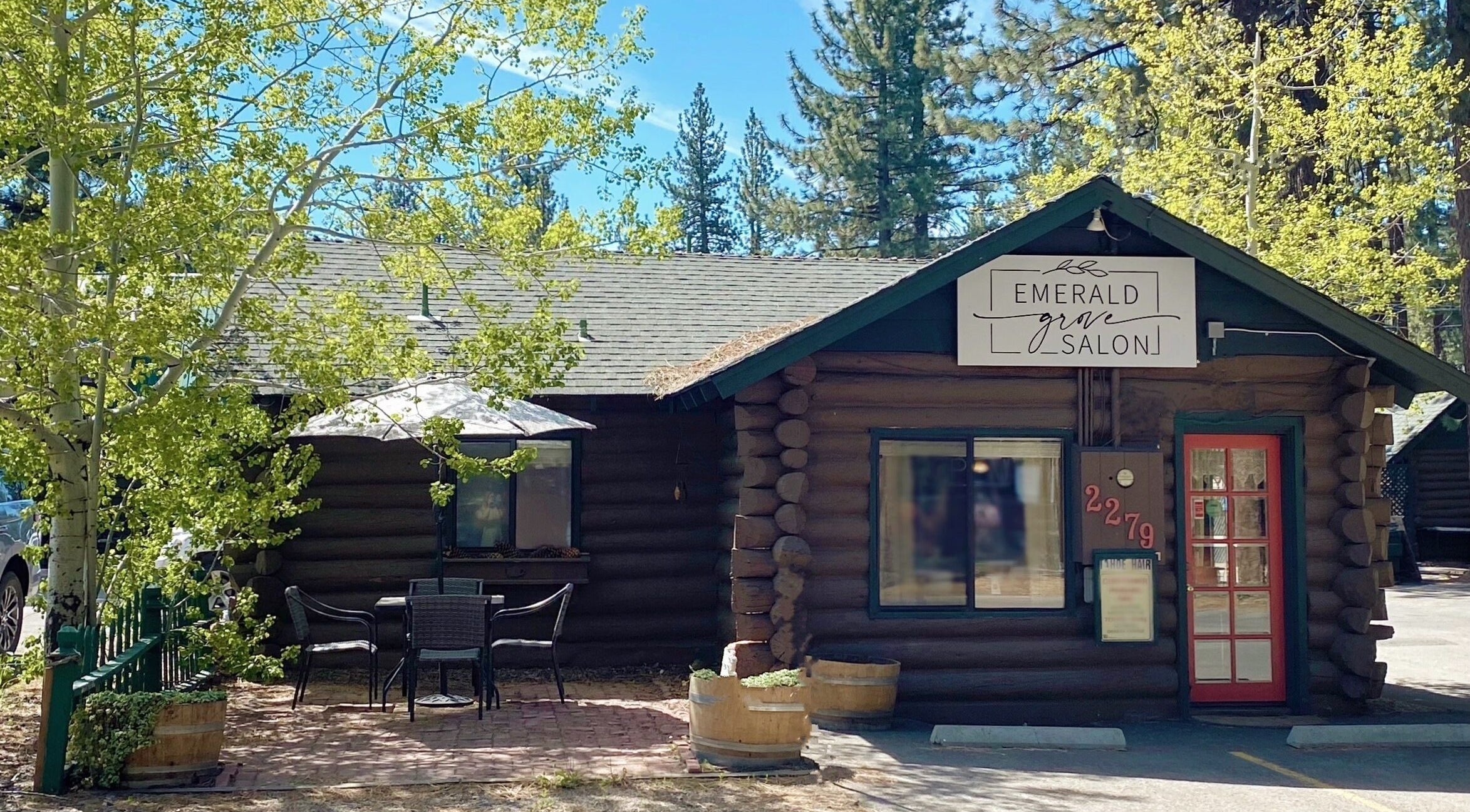 Emerald Grove Salon log cabin exterior in South Lake Tahoe, California, US with vibrant trees and seating area.