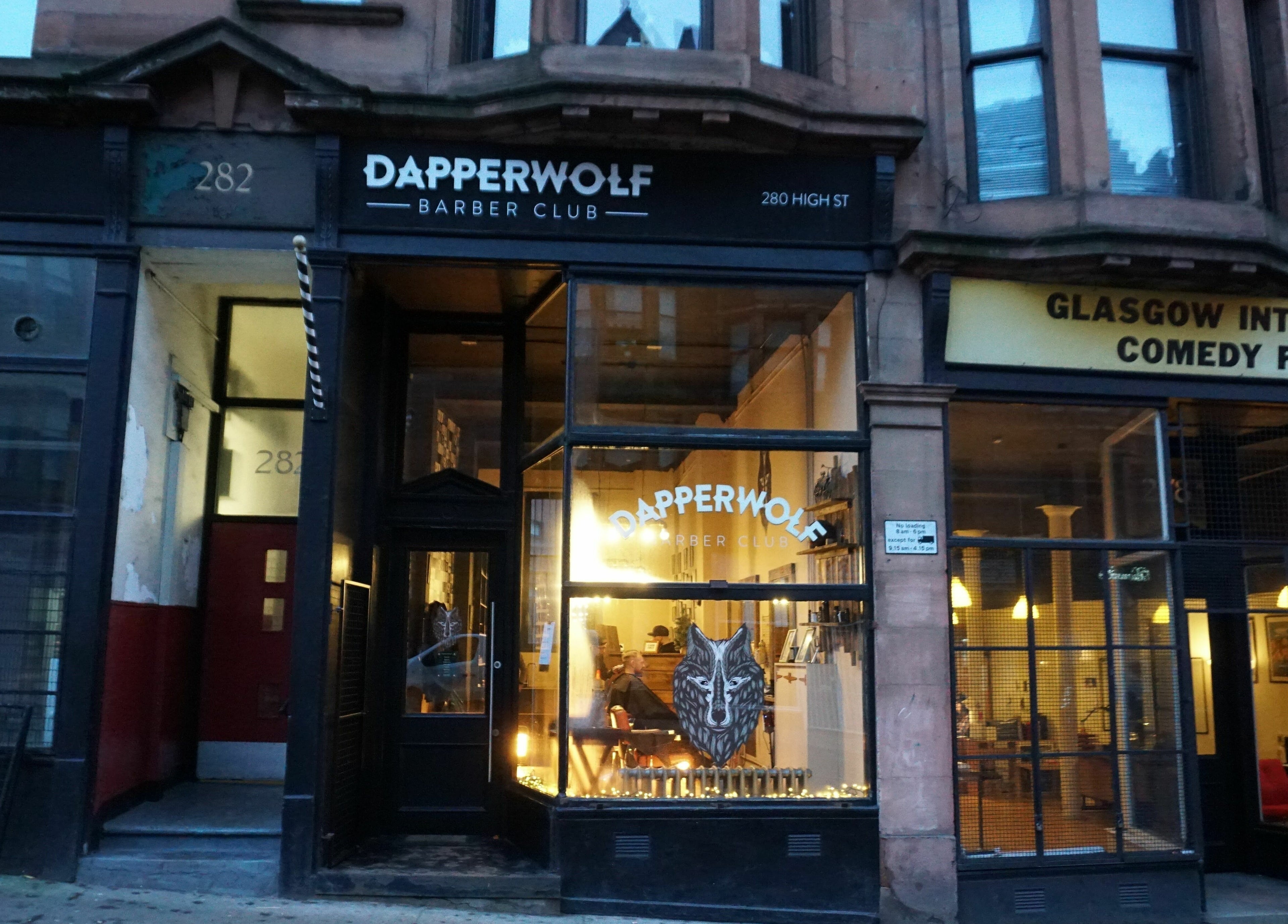 Dapperwolf Barber Club storefront at night in Glasgow, Scotland, GB, showcasing a stylish exterior.
