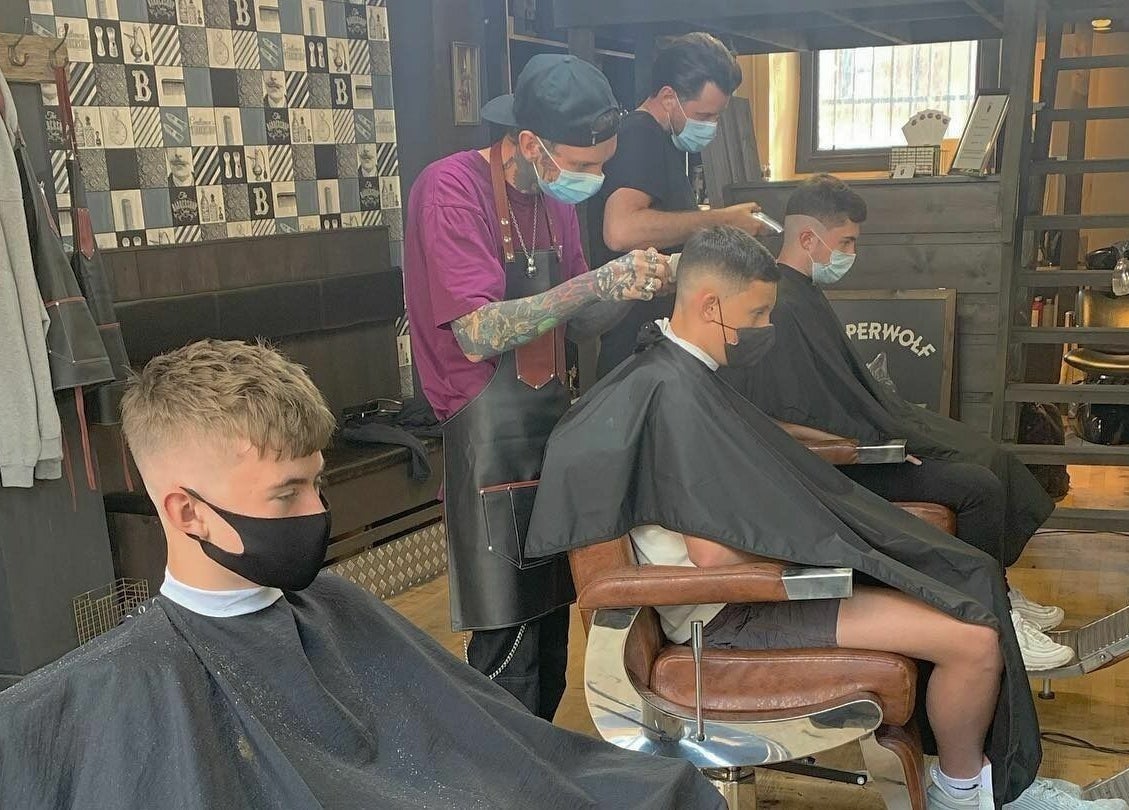 Barbers crafting haircuts at Dapperwolf, Glasgow, Scotland, GB.