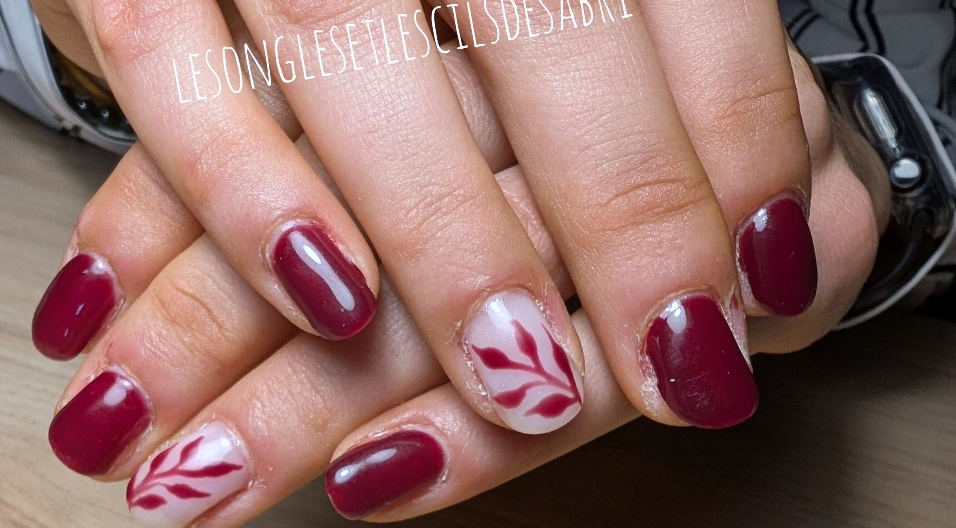 Manucure artistique à Lesonglesetlescilsdesabri, Cusset, Auvergne-Rhône-Alpes, FR. Vernis rouge et motif floral.