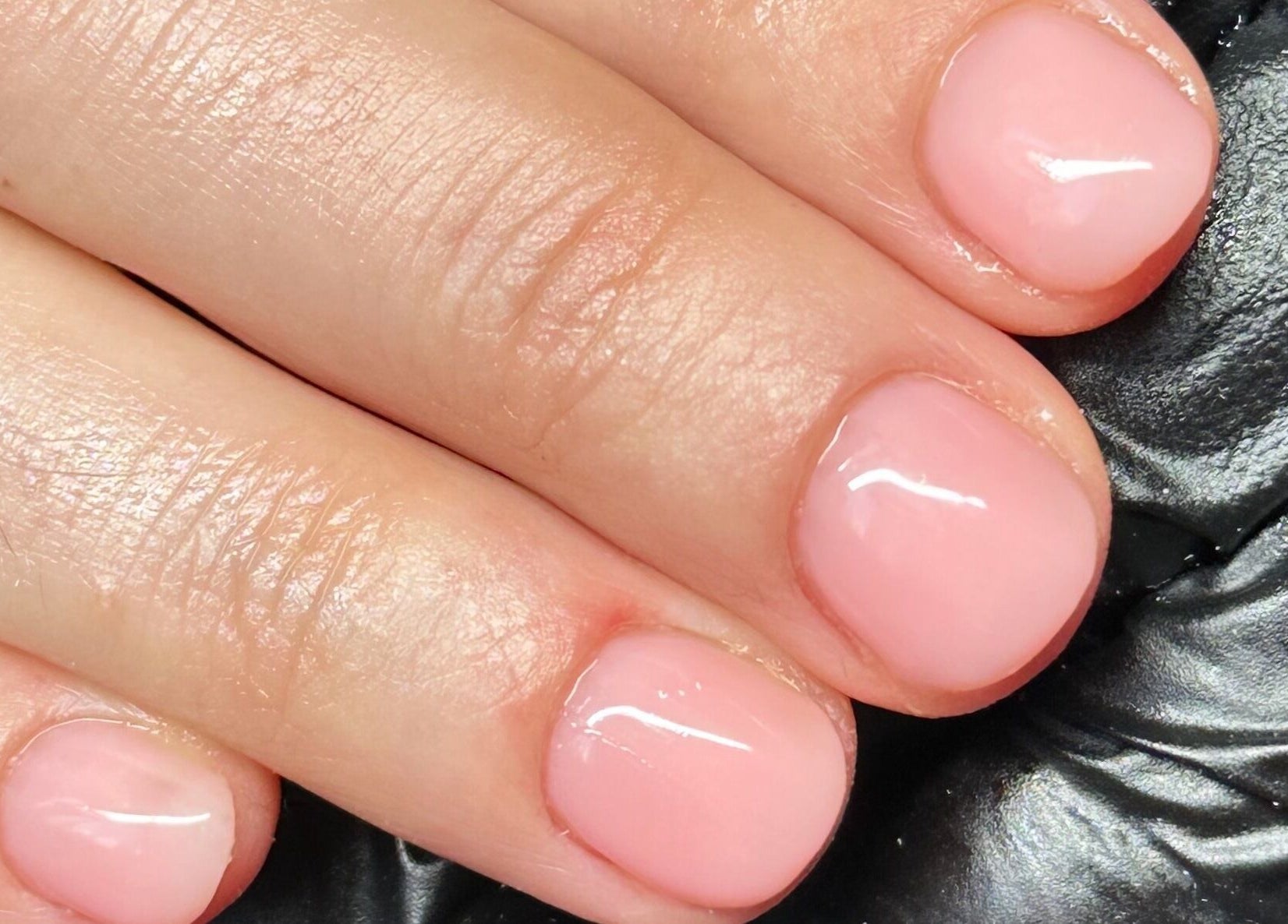 Close-up of a polished manicure at The Cure, Stockport, England, GB showcasing glossy pink nails.