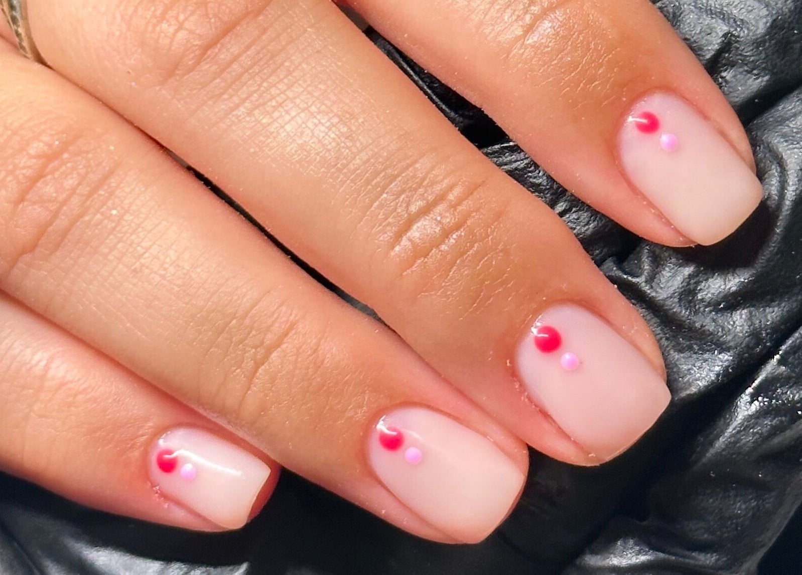 Stylish nail art with pink and red dots at The Cure, Stockport, England, GB.