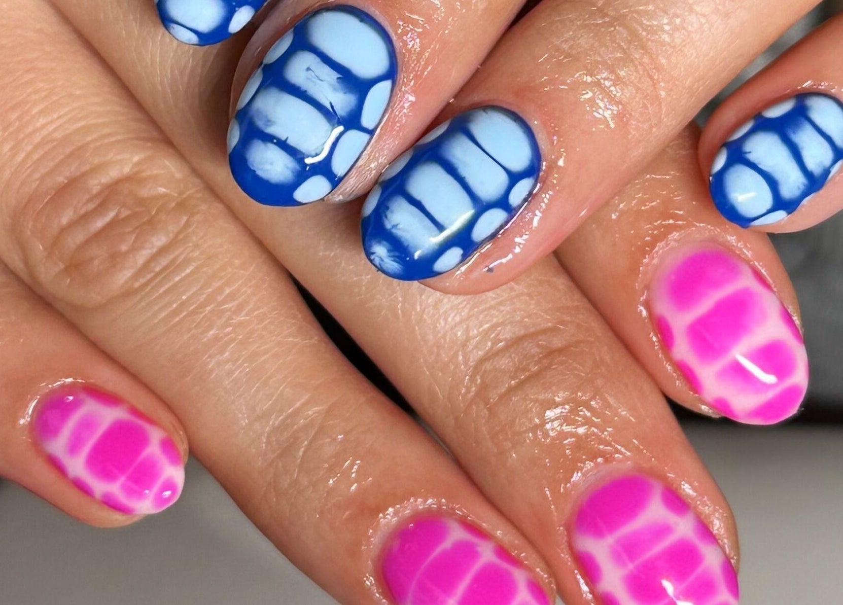 Colorful nail art at The Cure in Stockport, England, GB showcasing pink and blue designs.