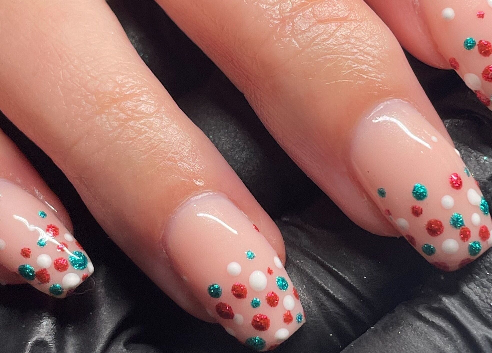 Polka dot nail art at The Cure in Stockport, England, GB showcasing vibrant red and teal designs.