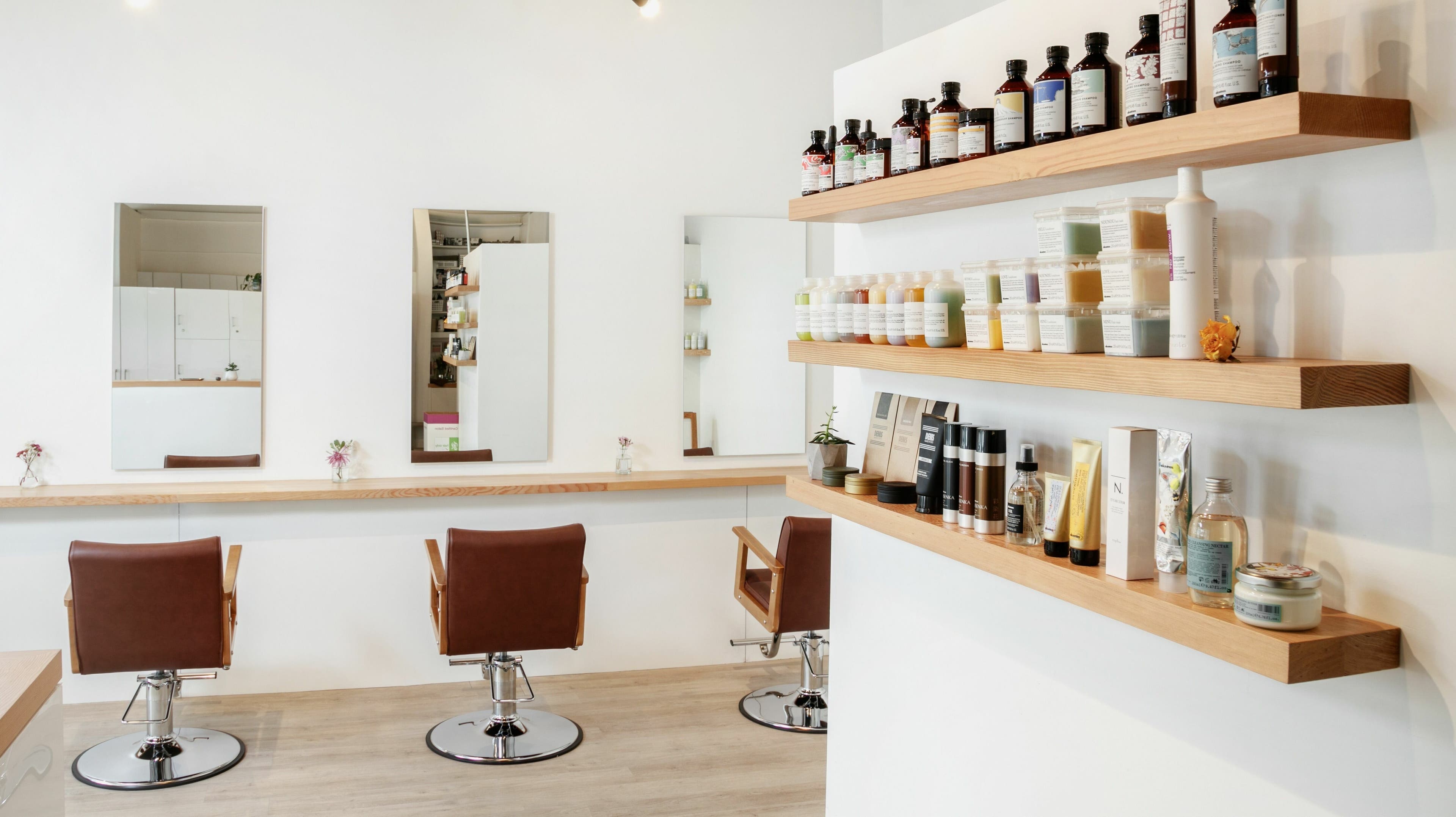 Stylish interior of Forme Hair Salon, Broadway in Vancouver, BC, CA featuring modern chairs and product shelves.