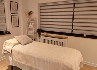 Cozy treatment room at Naked Glow Clinic, Hartland, England, featuring a restful bed and soothing decor.