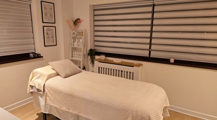 Peaceful treatment room at Naked Glow Clinic, Hartland, England, GB, featuring a cozy massage bed and calming decor.