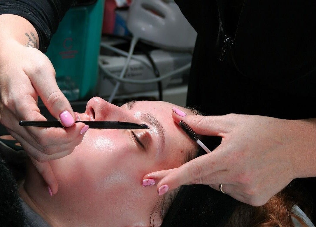 Eyebrow grooming at Naked Glow Clinic in Hartland, England, GB. Professional beautician shapes brows delicately.