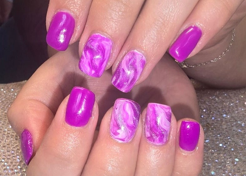Bright purple manicured nails with patterns at Naked Glow Clinic, Hartland, England, GB.
