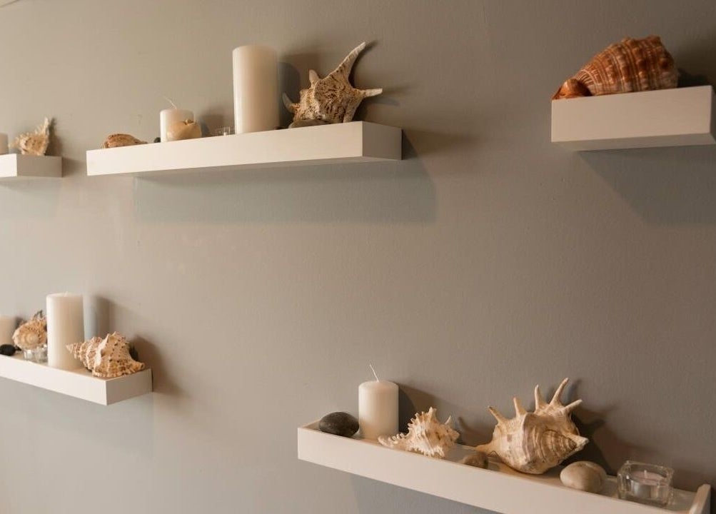 Elegant spa shelves with candles and shells at Comfy Spa, Vancouver, British Columbia, CA for a tranquil vibe.